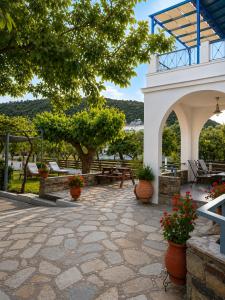 eine Terrasse mit Tischen, Stühlen und Blumen in der Unterkunft Alexandra Studios in Stafylos