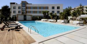 a large swimming pool with chairs and a building at Hotel Pineta Wellness & Spa in Ruvo di Puglia