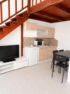 a living room with a television and a table and chairs at Holdfény apartman in Siófok