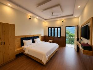 a bedroom with a large bed and a television at Cross Hill House Mussoorie in Mussoorie