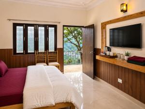 a bedroom with a bed and a flat screen tv at Cross Hill House Mussoorie in Mussoorie