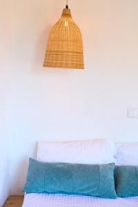 a pendant light above a bed with blue pillows at Billion Stars Studio in Thymonia Beach