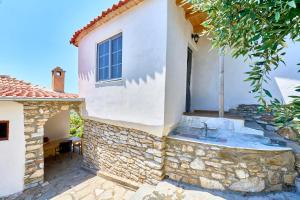 a white house with a window and a stone wall at Billion Stars Studio in Thymonia Beach