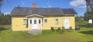 a yellow house with a table and chairs in front of it at Riverside Restplace in Tornio