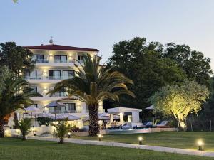 a hotel with a palm tree in front of a building at domus hospitality in Vourvourou