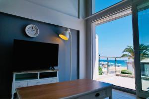 a living room with a tv and a view of the beach at Villa Mediterrane Hotel in Iraklitsa