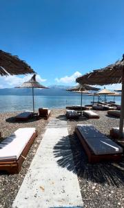 a group of beds on a beach with umbrellas at Hotel Restorant Binjaket in Pogradec