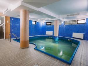 a large swimming pool in a room with blue tiles at Complex Turistic Le Baron Vatra Dornei in Vatra Dornei