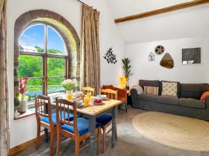 a living room with a table and chairs and a couch at Smiddy Cottage Hawkridge in Dulverton
