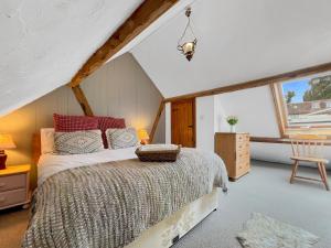 a bedroom with a bed and a chair and a window at Smiddy Cottage Hawkridge in Dulverton