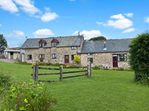 a stone house with a fence in front of it at Smiddy Cottage Hawkridge in Dulverton