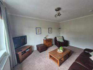 a living room with a couch and a tv and a table at Spacious 2 Bedroom Flat in Coatbridge in Coatbridge