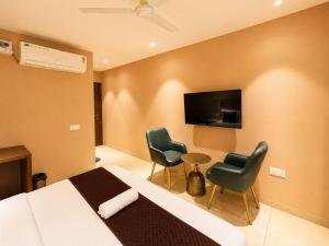 ein Hotelzimmer mit einem Bett, zwei Stühlen und einem Fernseher in der Unterkunft Hotel Supreme Regency in Ludhiana + 22 Fotos