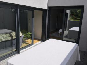 a bedroom with a white bed and glass windows at Stunning New Apartment Senningerberg in Niederanven