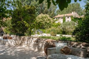 a garden with a couch and a stone wall at Casa tudo bem in Pernes-les-Fontaines