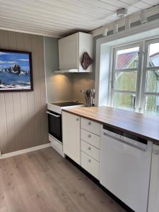 eine Küche mit weißen Schränken und einem großen Fenster in der Unterkunft Vikanhuset in Andenes