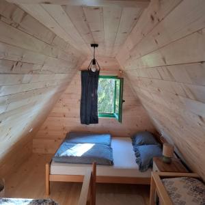 a bed in a wooden room with a window at Vikendica Breza 2 in Zaovine +12 photos
