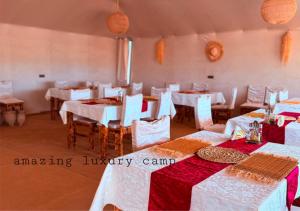 a dining room with white tables and white chairs at Amazing Luxury Camp in Merzouga