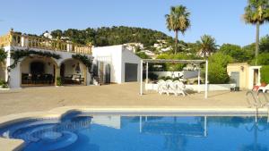 a villa with a swimming pool in front of a house at El Rafalet in Jávea