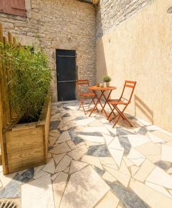 a patio with two chairs and a table and a plant at Côte-et-vins Gîte Le Cocon in Chagny