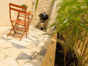 a wooden chair sitting on a patio with a grill at Côte-et-vins Gîte Le Cocon in Chagny