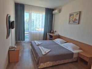 a hotel room with a bed with two towels on it at Ahilea Hotel - Free Pool Access in Balchik
