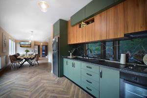 a kitchen with green cabinets and a dining room at Residence by Carol&Vladi in Târgu Ocna