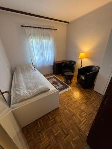 a bedroom with a bed and a couch and chairs at Vila Ljubinka in Brežđe