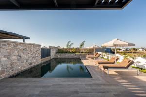 an image of a swimming pool with lounge chairs next to a stone wall at SoleLuna - The Villas Project in Marmaroto