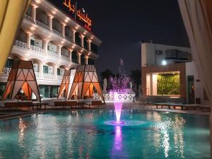 a swimming pool with a fountain in front of a building at Mövenpick Grand Al Bustan in Dubai