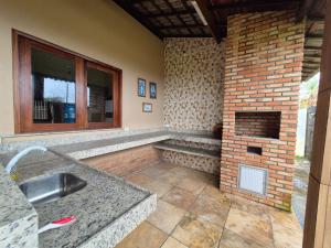 a kitchen with a brick fireplace and a sink at Casa Brisas 17 in Luis Correia