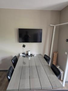 a dining room table with chairs and a flat screen tv at Appartment on Dorpsstraat in Bleskensgraaf