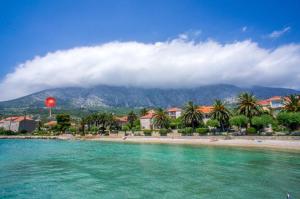 a beach with palm trees in front of a mountain at Apartment Seaside Orebić in Orebić