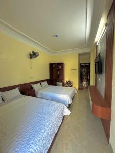 a hotel room with two beds and a flat screen tv at Huệ Vinh Hotel in Cửa Lô