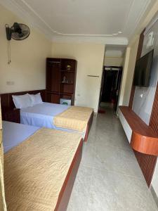 a hotel room with two beds and a flat screen tv at Huệ Vinh Hotel in Cửa Lô