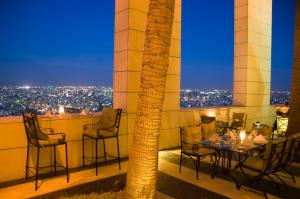 a table and chairs on a balcony with a palm tree at Le Royal Amman in Amman