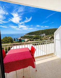a red table and chairs on a balcony with the ocean at Apartments Marija Magdalena in Hvar