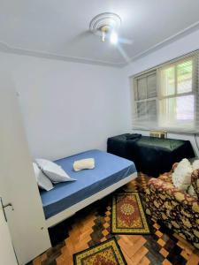 a bedroom with a blue bed and a couch at Pousada in Porto Alegre