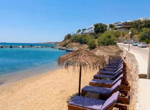 a row of beach chairs and umbrellas on a beach at Anchorage Paros Boutique & Private Beach in Piso Livadi