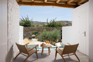 a patio with a table and chairs and a view at Oliving Mykonos Luxury Suites in Klouvas