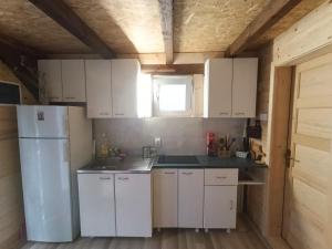a kitchen with white cabinets and a white refrigerator at Stevanova brvnara in Zlatibor