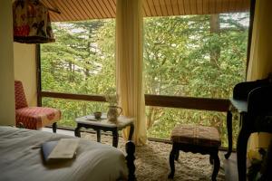 a bedroom with a bed and a large window at MONKEY RESORT in McLeod Ganj