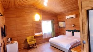 a bedroom with a bed and a chair in a room at Serenity Bungalows in Cıralı