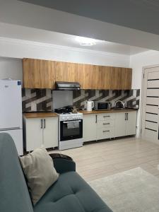 a kitchen with white cabinets and a blue couch at Атлантис in Chon-Sary-Oy