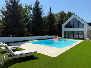 a swimming pool with two chairs and a house at Kálló Villa in Nagykálló