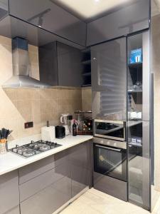 a kitchen with stainless steel appliances and black cabinets at F&F Villa in Tema +9 photos