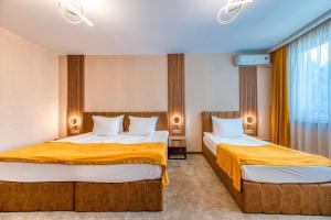 two beds in a hotel room with yellow sheets at Hotel Montecito in Sofia +79 photos