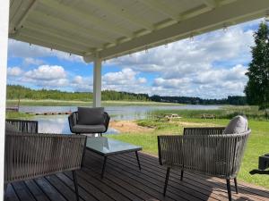 a porch with chairs and a table and a lake at Lobotka sadama puhkemaja in Slobotka