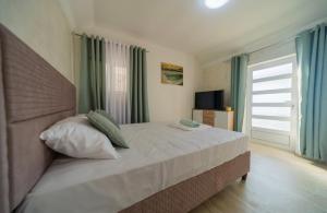 a bedroom with a large bed with green curtains at The Best Lake View Studios Borisic in Vranjina