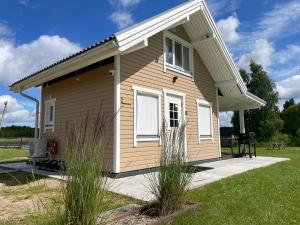 a small brown house with white windows and grass at Lobotka sadama puhkemaja in Slobotka +6 photos